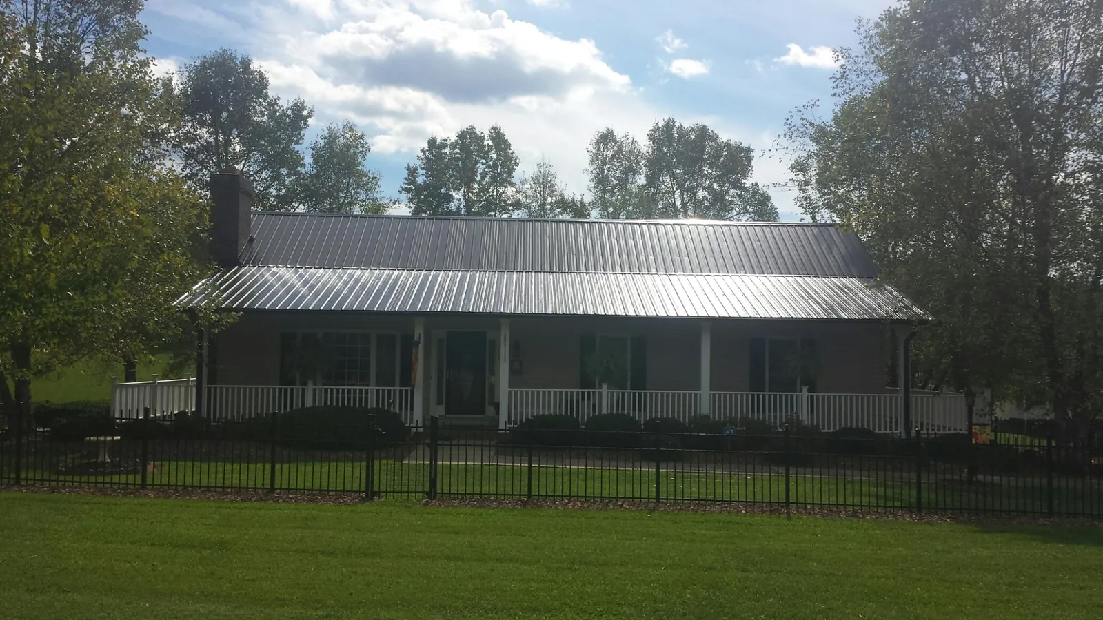 Gray metal roof on a brick ranch with a full width front porch — Gutter Guard Installation work by our crew in Fort Washington