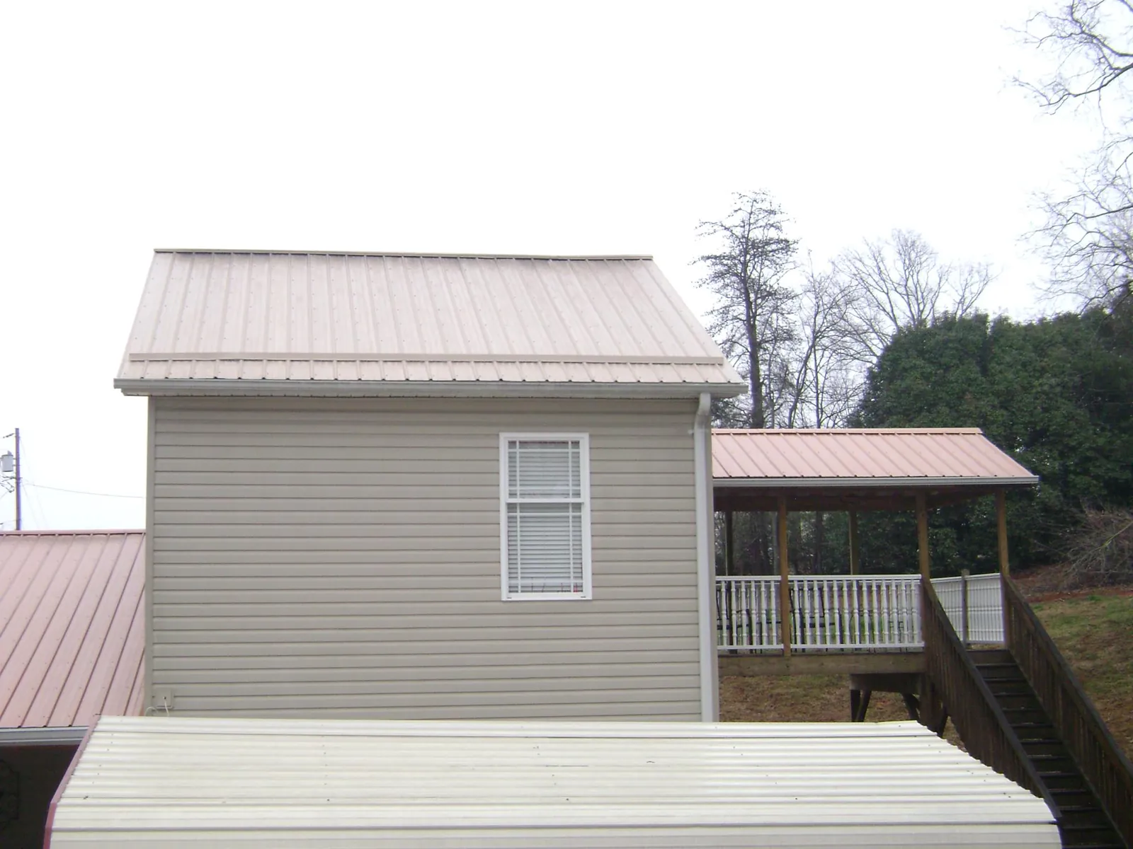 Tan metal roofs on a two story addition and attached porch, from a Roof Replacement job in Fort Washington