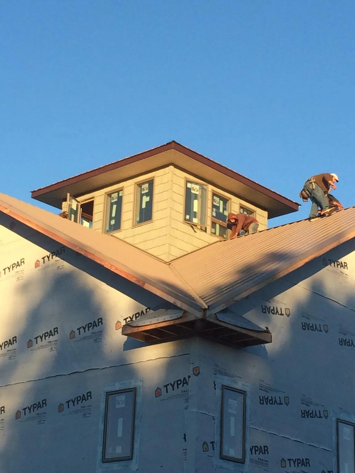 Roofers working around a rooftop cupola on a new metal roof at sunset — Roof Waterproofing in Fort Washington by Roofing Brothers